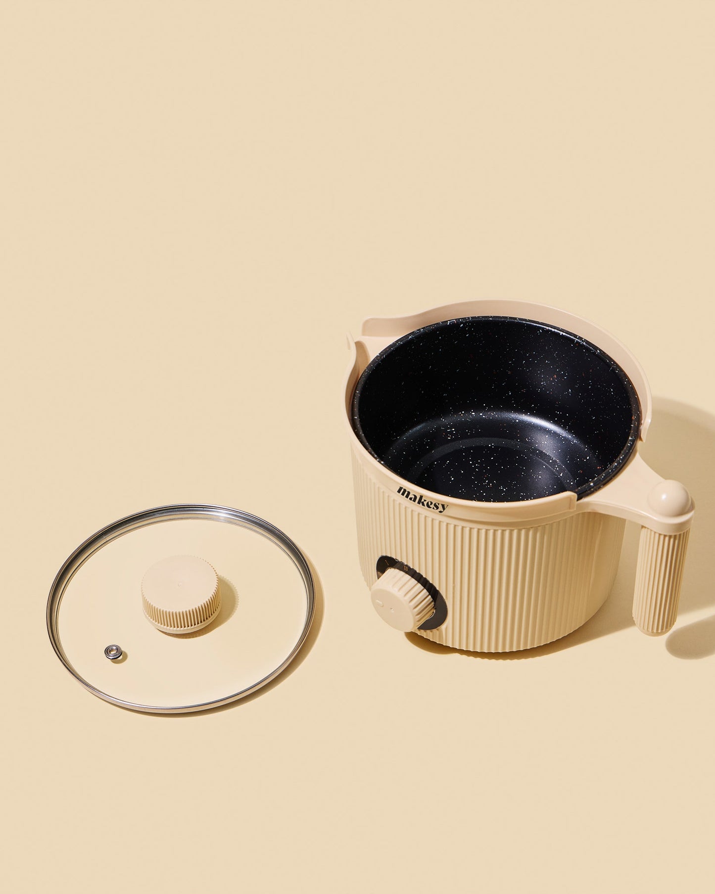 Beige electric hot pot with black interior on a beige background