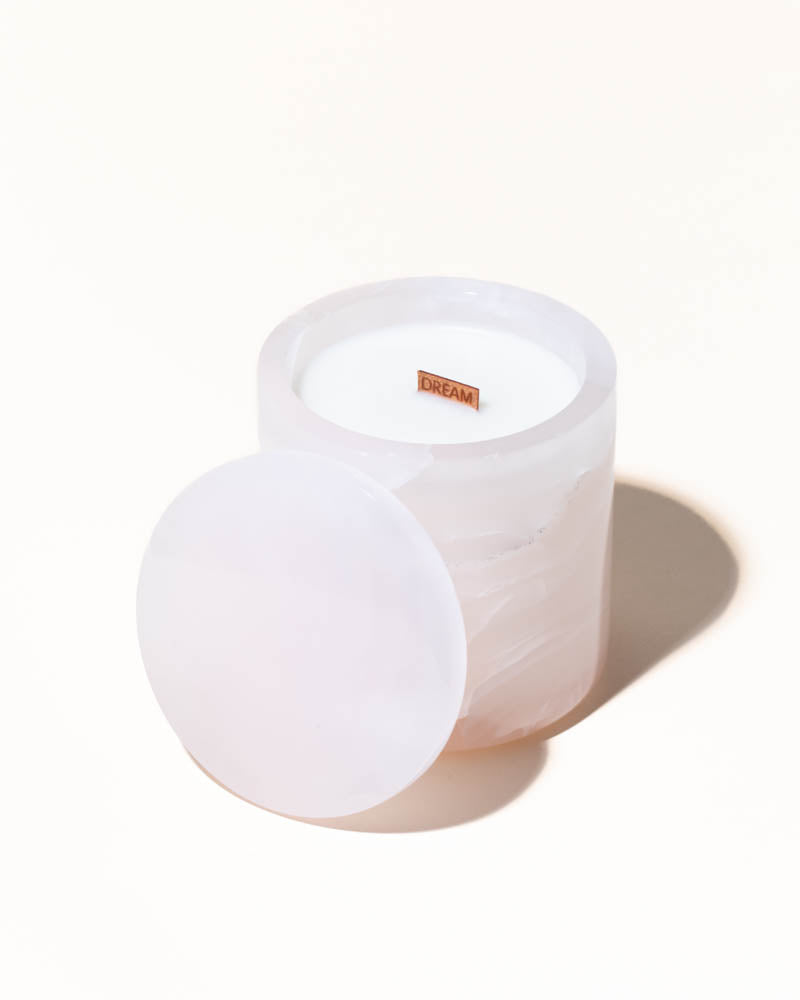 White candle in a glass container on a white background