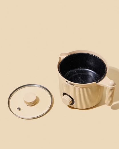 Beige electric hot pot with black interior on a beige background