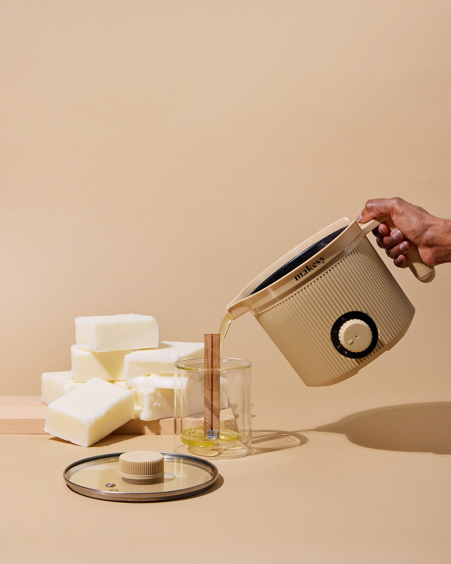 Person pouring liquid from a beige container into a glass on a beige background