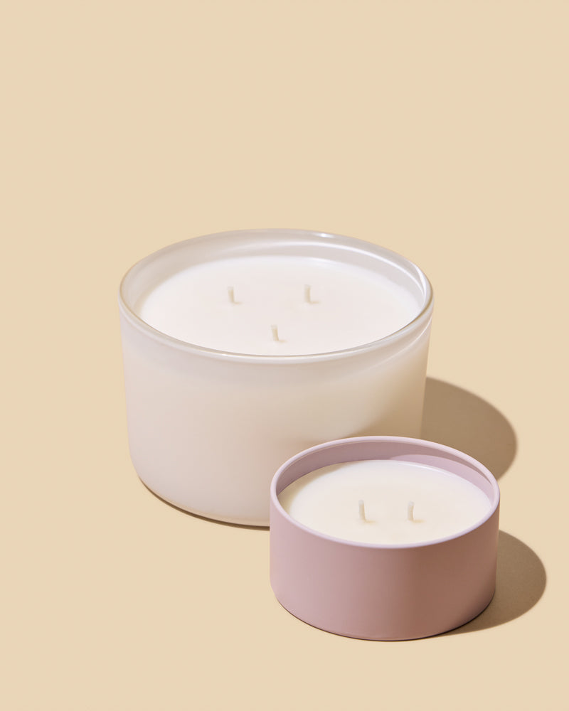 Two candles in white and pink containers on a beige background
