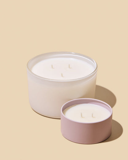 Two candles in white and pink containers on a beige background