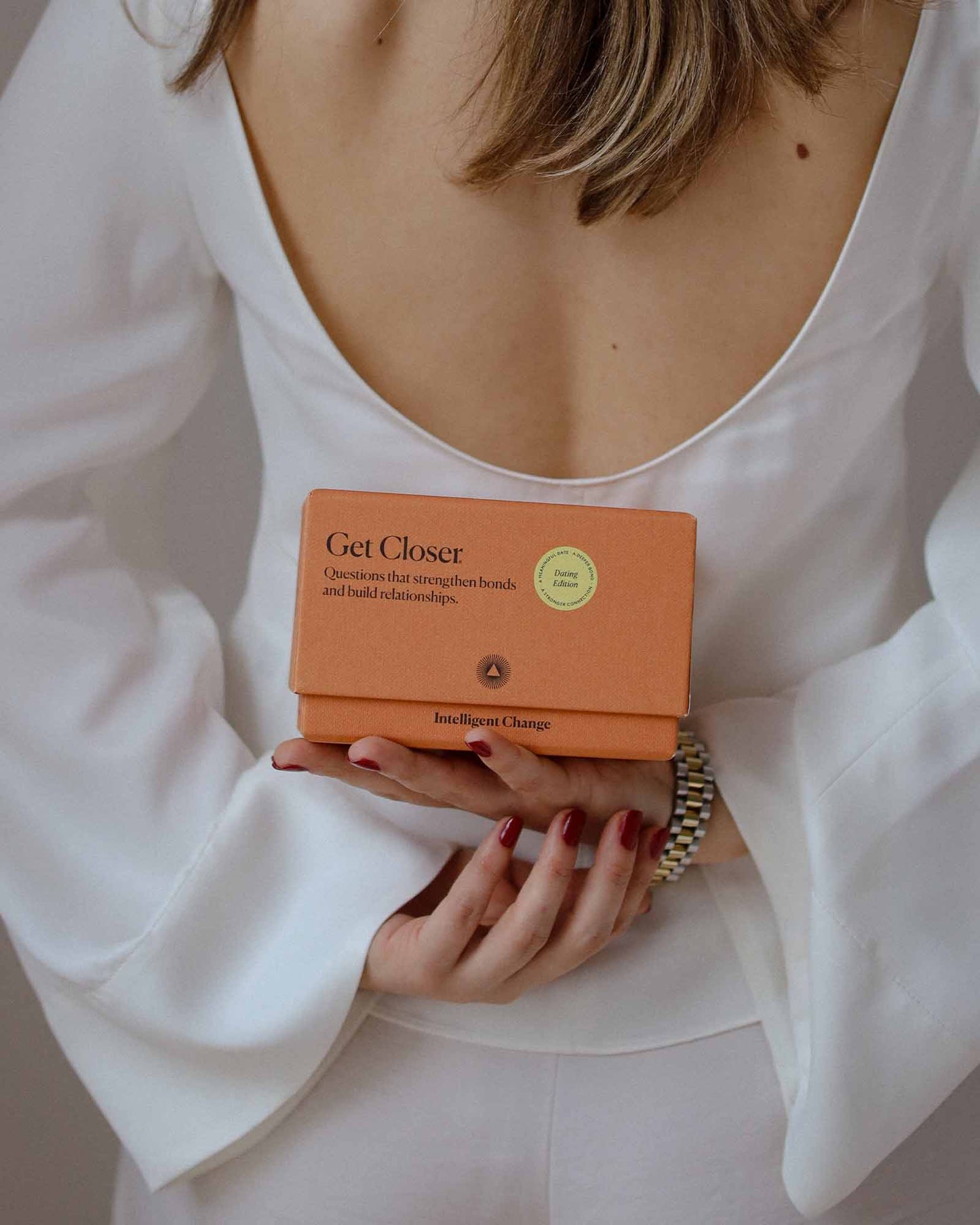 Person holding an orange product box labeled 'Get Closer' with a white background