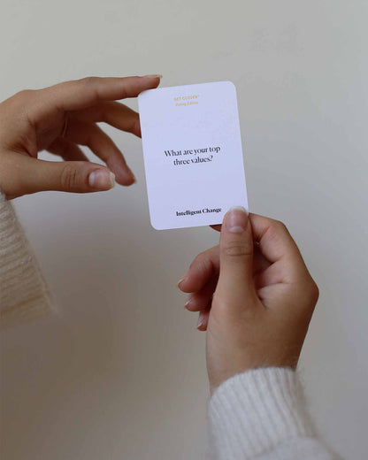 Hand holding a card with 'What are your top three values?' question on a plain background