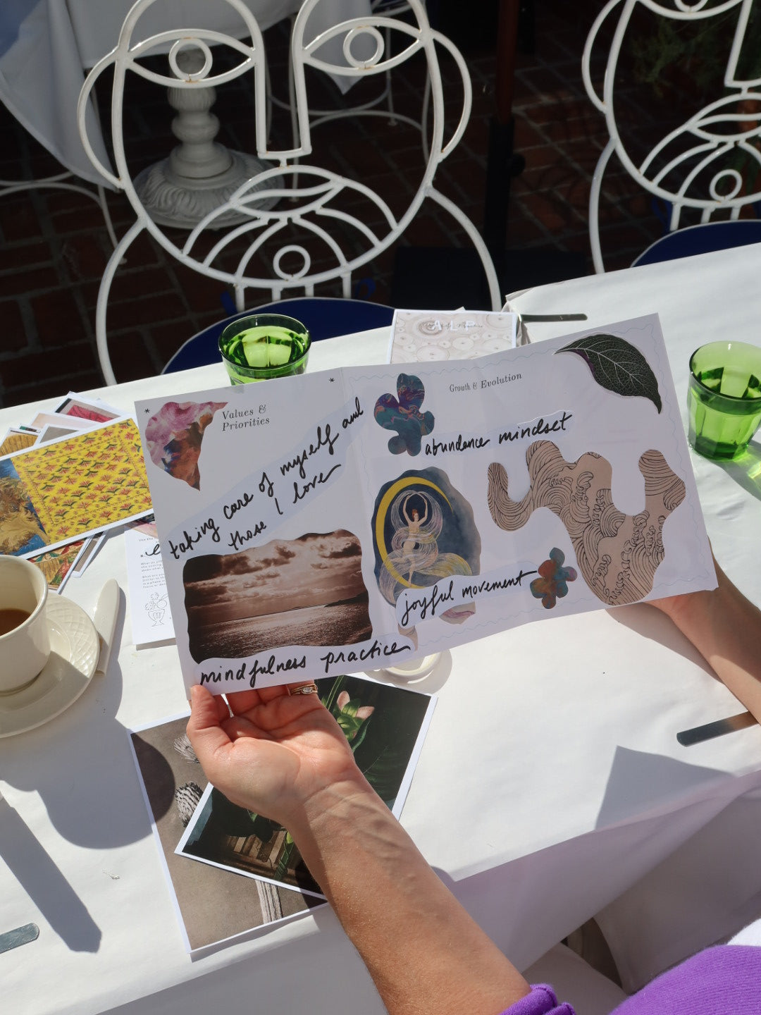 Person holding a card with mindfulness activities at an outdoor cafe.