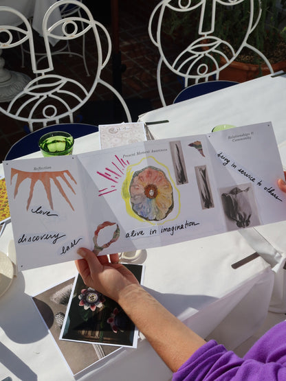 Person holding a collage of images and text on a table with decorative elements.
