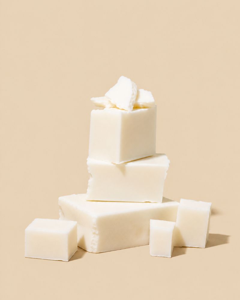 White rectangular bars of soap stacked and arranged on a warm beige background.